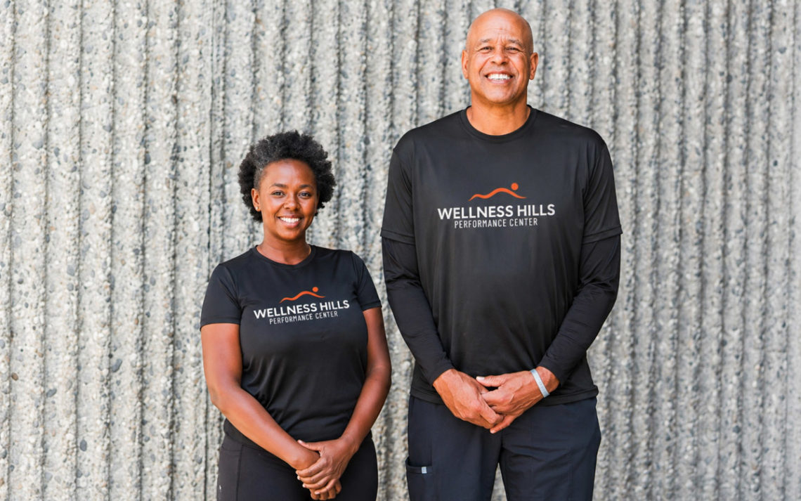 Bodyworkers, David Cantrell and Sheila Maingi stand together in front of a wall.
