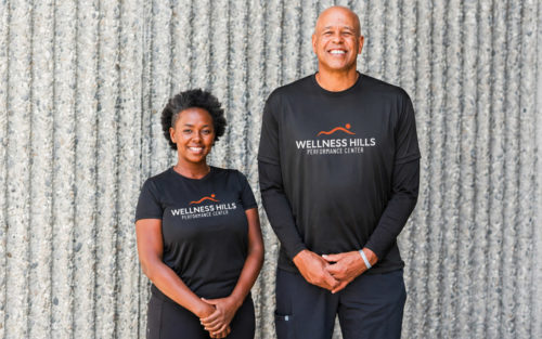 Bodyworkers, David Cantrell and Sheila Maingi stand together in front of a wall.